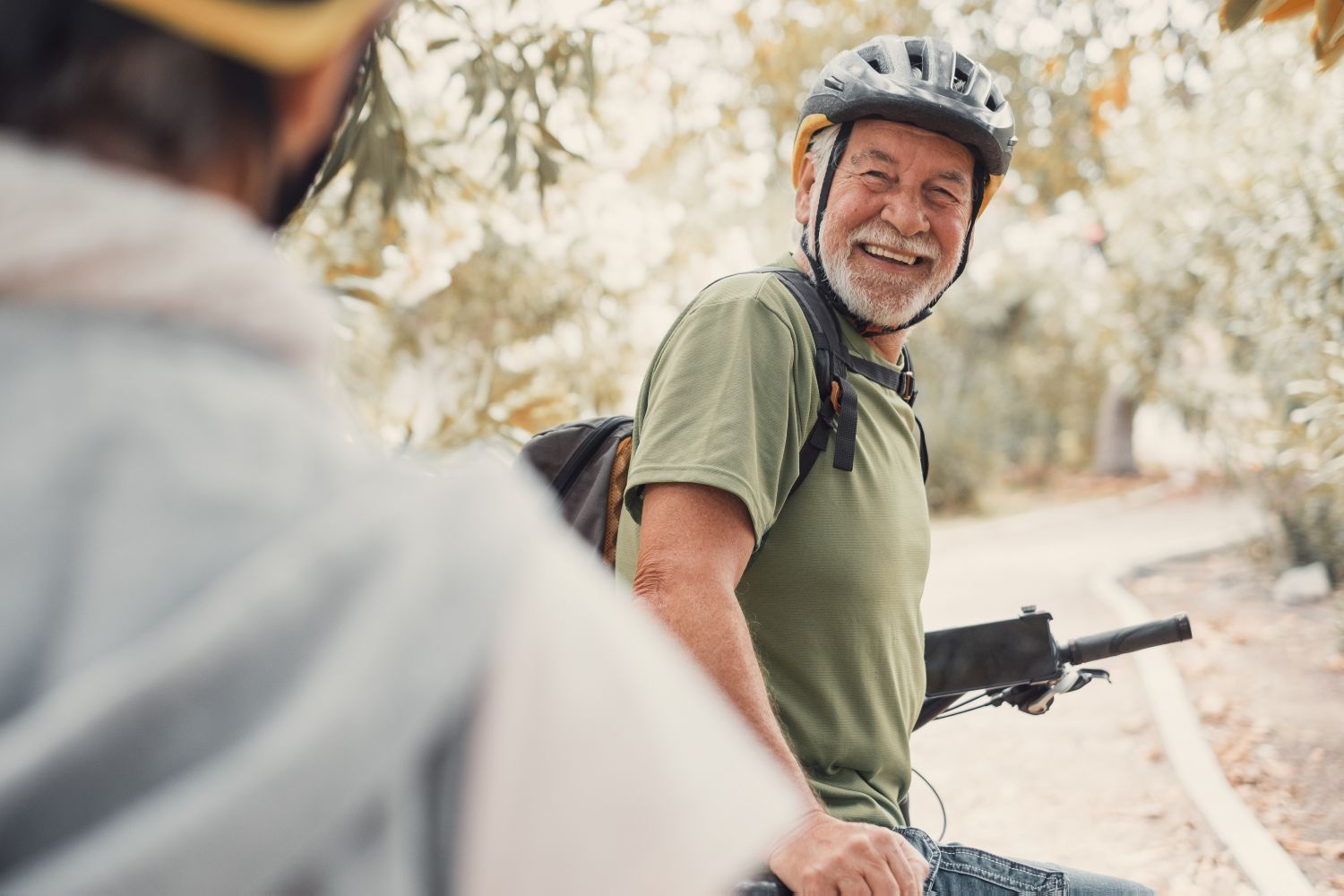 older gentleman riding a bike on a trail in the forest